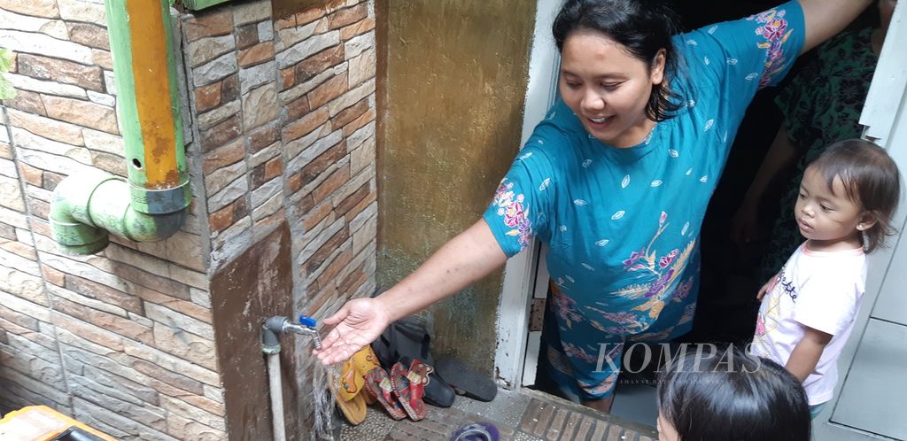 Dewi (32), warga Cilincing, Kecamatan Kramat Jati, Jakarta Timur, mengecek air bersih di rumahnya, Selasa (5/12/2023). 
