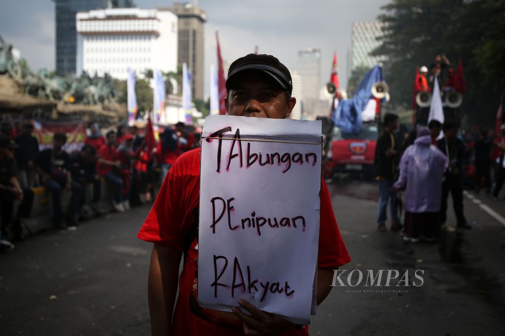 Seorang peserta aksi membawa poster bertuliskan penolakan terhadap tabungan perumahan rakyat (tapera) di kawasan Patung Kuda Arjuna Wijaya, Jakarta, Kamis (27/6/2024). 