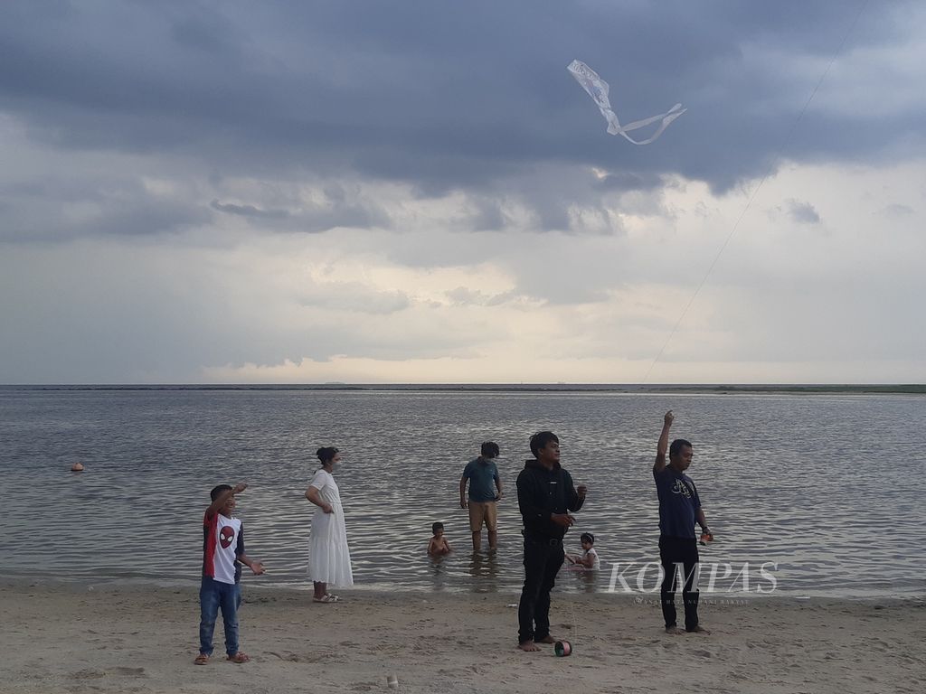 Pengunjung bermain layang-layang di tepi pantai Ancol, Jakarta Utara, pada Kamis (2/6/2022) sore.
