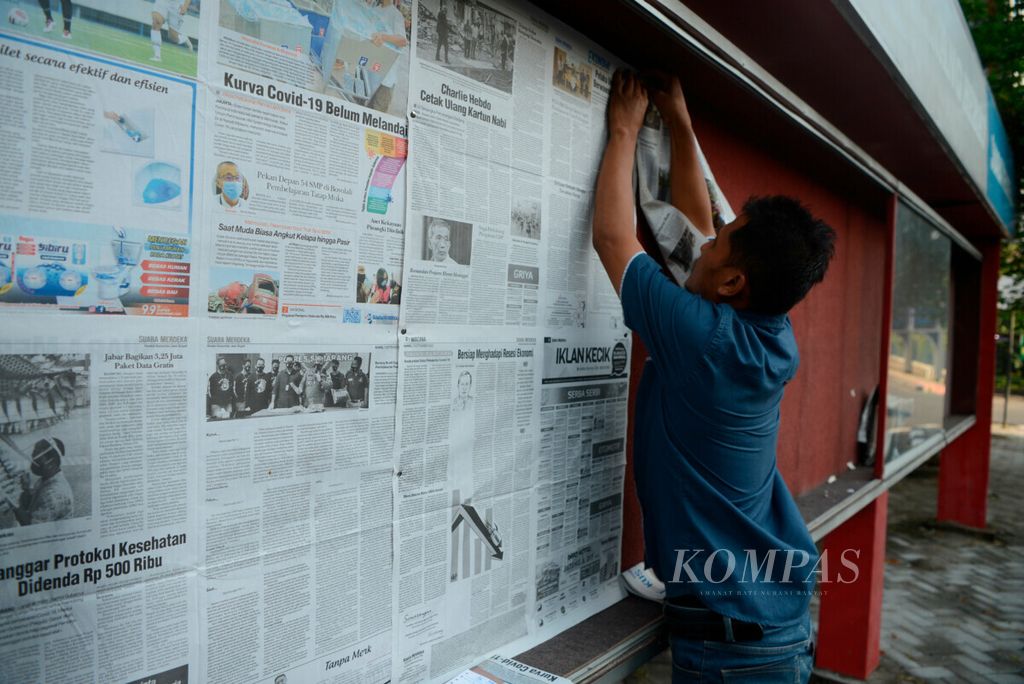 Pekerja memasang koran terbitan terbaru pada papan di Jalan Sultan Agung, Kota Semarang, Jawa Tengah, Kamis (3/9/2020). Perkembangan teknologi dan media daring berpengaruh besar terhadap tren media cetak seperti koran yang terus menurun pembacanya. Media cetak pun saat ini harus beradaptasi melalui berbagai cara untuk bertahan.