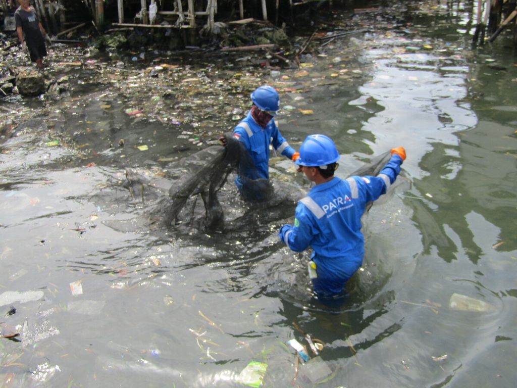 Petugas membersihkan sampah plastik dan limbah oli yang mencemari kawasan pesisir Kecamatan Panjang, Kota Bandar Lampung, Lampung, pada Kamis (10/3/2022). 