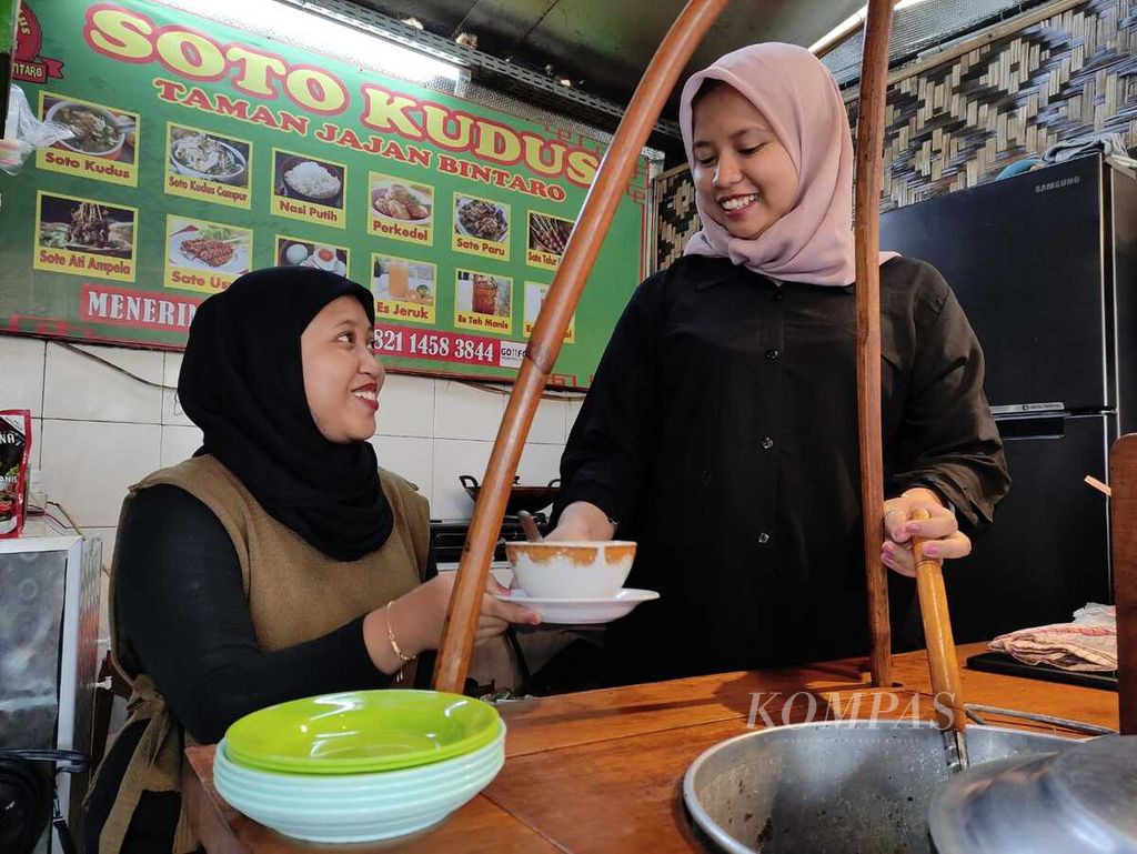 Ismiyati Handayani (kanan) asal Kebumen, Jawa Tengah, dan Wahana Safitri, sesama pegawai Soto Kudus Taman Jajan Bintaro, menyiapkan hidangan. Mereka sempat mengalami gegar budaya karena pembayaran yang serba digital.
