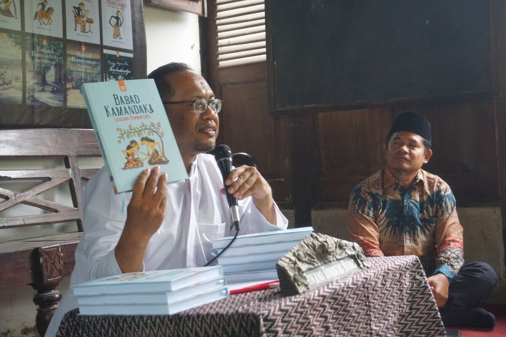 Nassirun Purwokartun menunjukkan buku seri <i>Babad Pasir</i> di Bale Pustaka, Desa Mandirancan, Kebasen, Banyumas, Jawa Tengah, Sabtu (7/10/2023).
