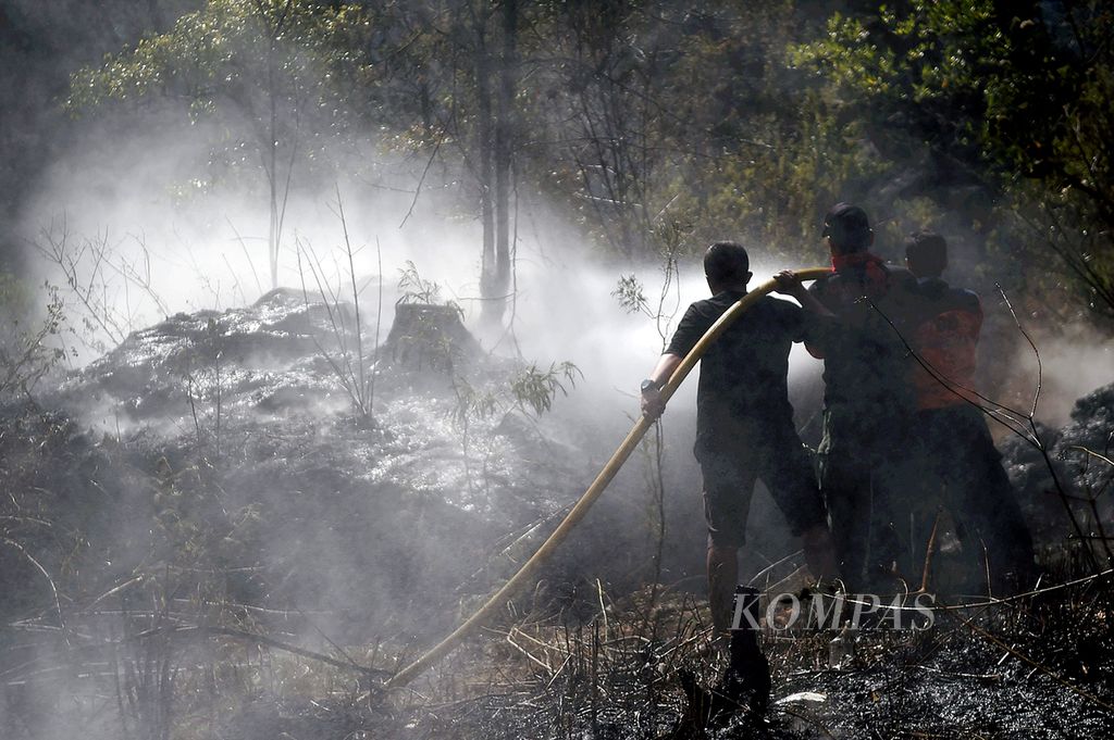 Petugas gabungan berusaha membasahi area yang terbakar di lereng Gunung Lawu di sekitar gerbang pendakian Cemoro Sewu, Desa Ngancar, kecamatan Plaosan, Kabupaten Magetan, Jawa Timur, Senin (26/10/2015).  Tahun 2023, kebakaran terjadi lagi di Gunung Lawu.