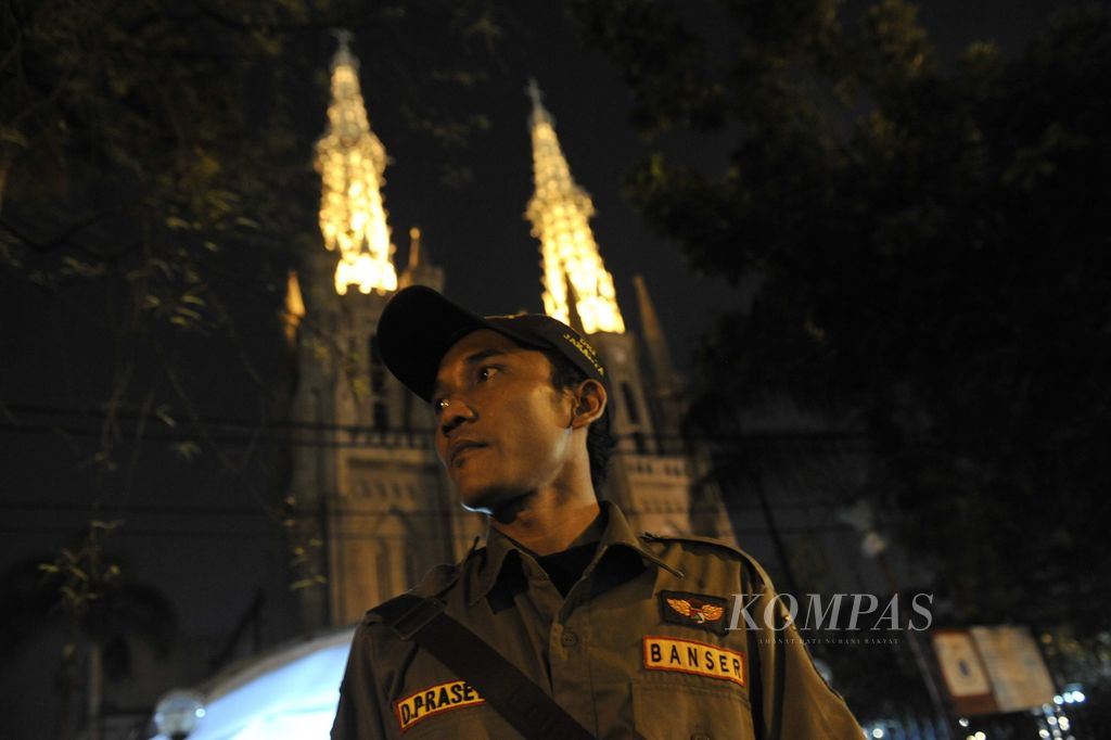 Anggota Barisan Ansor Serbaguna (Banser) Nahdlatul Ulama ikut menjaga keamanan di luar Gereja Katedral, Jakarta, saat berlangsung misa malam Natal, pada 24 Desember 2011. Misa yang dihadiri ribuan jemaat tersebut berlangsung khidmat. 