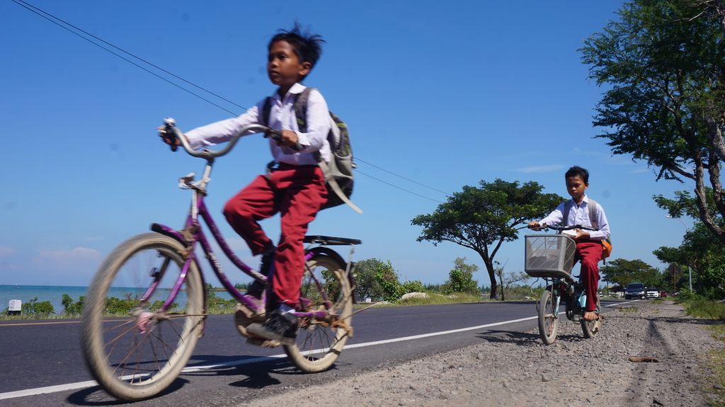 Anak-anak nelayan bersepeda sepulang sekolah di Jalan Raya Pamekasan-Sumenep, Pulau Madura, Jawa Timur, Senin (20/6/2022). 