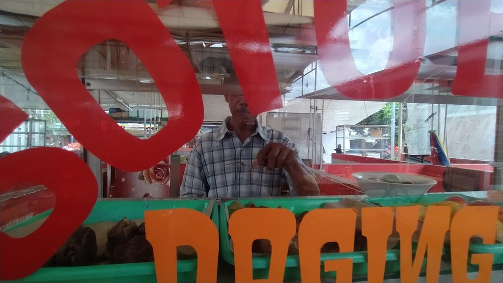 Daryo (64), pedagang, tengah menyiapkan semangkuk soto Betawi di Lokbin PKL Taman Kota Intan, Jakarta, Senin (12/12/2022). Setiap hari, Daryo menghabiskan malam di bilik kios tersebut karena tak punya tempat tinggal.