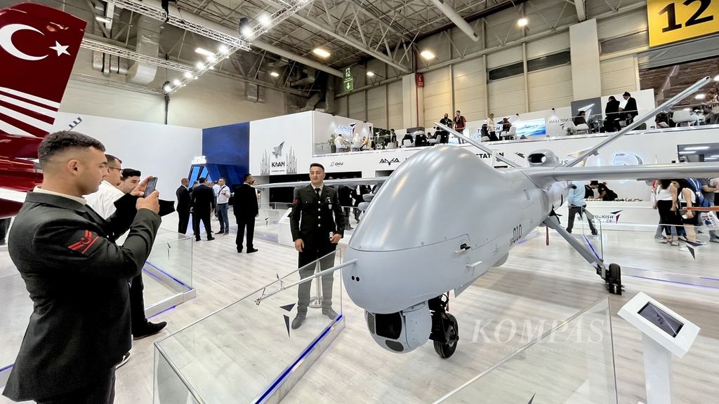 Visitors take photos alongside the unmanned Anka aircraft produced by Turkish Aerospace on display at the International Defence Industry Fair (IDEF) in Istanbul, Turkey on Wednesday (26/7/2023).