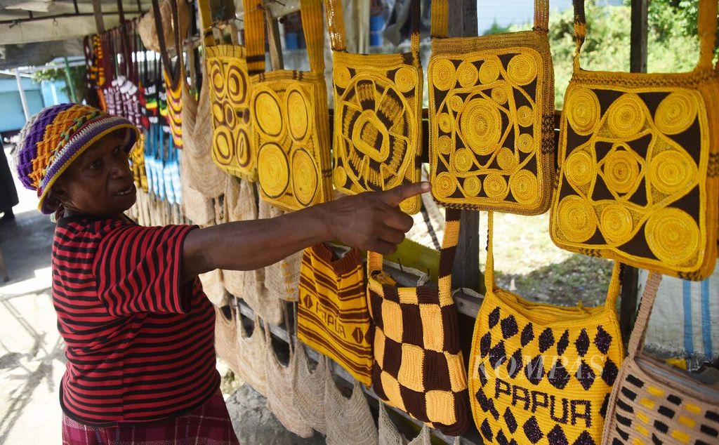 Penjual noken menjelaskan tentang harga dan material yang digunakan di sentra penjualan noken di Jalan Yos Sudarso, Kabupaten Nabire, Papua, Rabu (28/4/2021). 