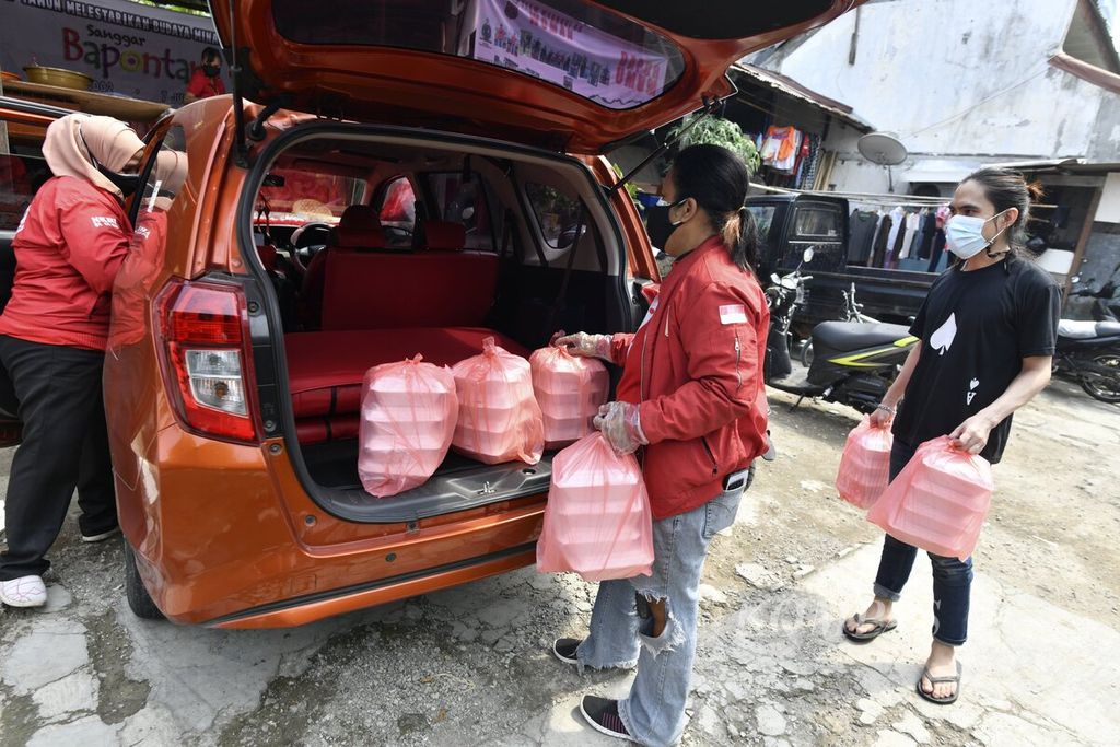 Sejumlah sukarelawan memasukkan nasi kotak ke dalam mobil di dapur umum peduli Covid-19 di di Karet Semanggi, Setiabudi, Jakarta Selatan, untuk kemudian didistribusikan kepada warga, Kamis (8/7/2021).
