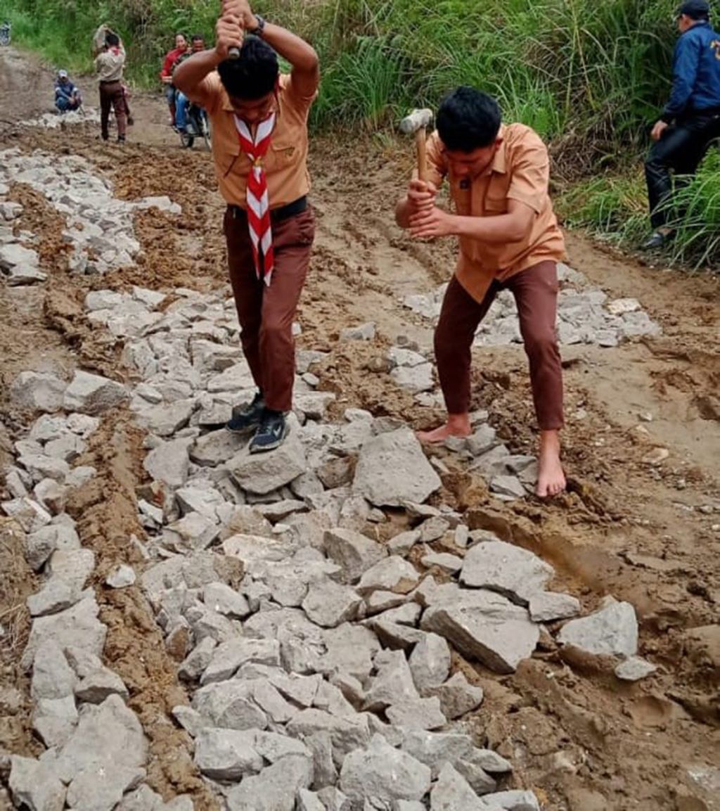 Siswa SMA bergotong royong menimbun jalan rusak dengan batu secara swadaya di jalan provinsi di Kecamatan Borbor, Kabupaten Toba, Sumatera Utara, November 2022. Sudah belasan tahun jalan di sentra produksi pertanian itu tidak diperbaiki.