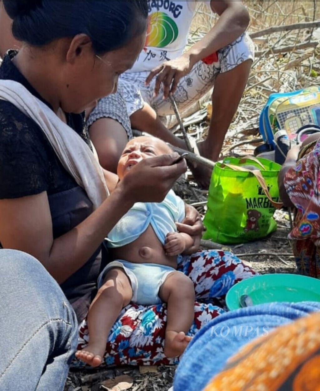 Seorang ibu korban penggusuran sedang memberi makan anak bayi di hutan, saat mengungsi, setelah rumah mereka digusur paksa.