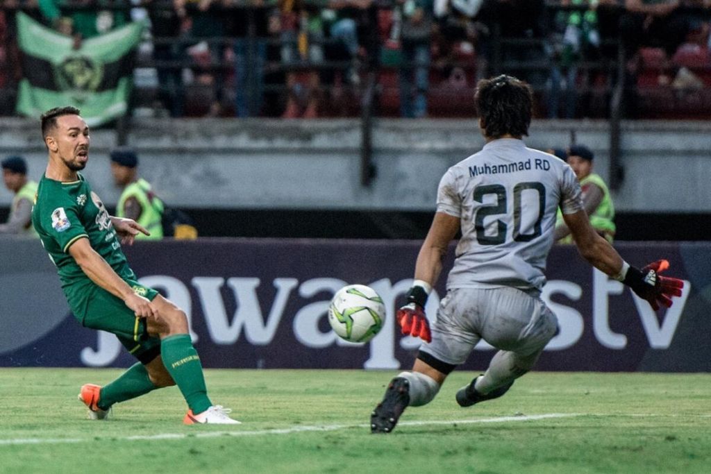 Aksi gelandang Persebaya Surabaya, Damian Lizio, saat berhadapan dengan kiper Madura United, Muhammad Ridho, pada laga pertama semi final Piala Indonesia, Rabu (19/6/2019), di Stadion Gelora Bung Tomo. Pertandingan berakhir dengan skor 1-1.