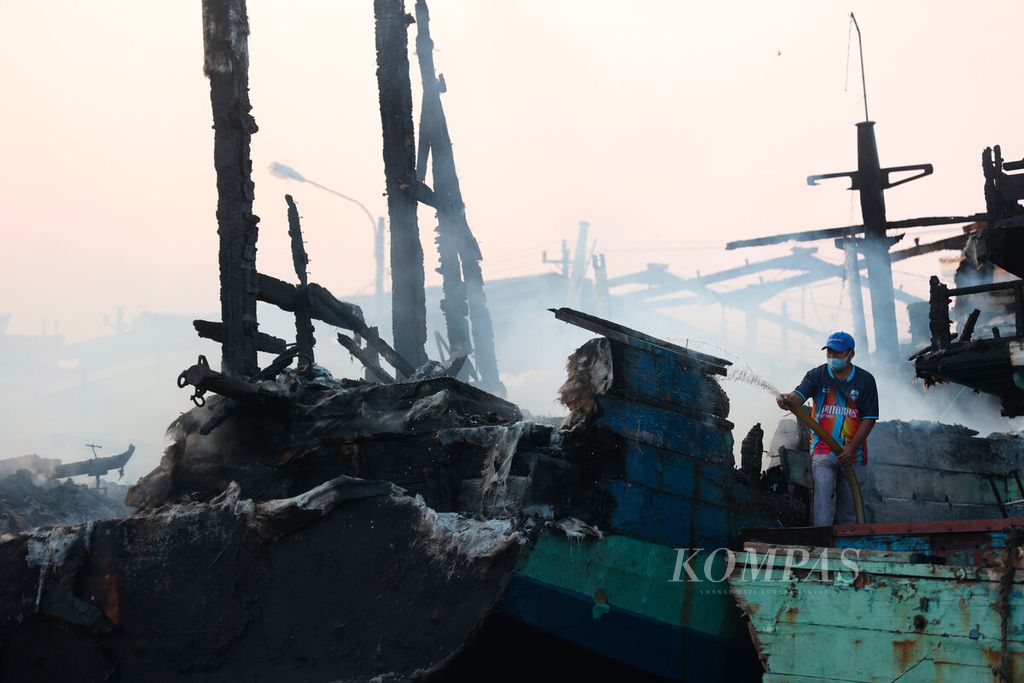 Warga berusaha memadamkan sisa api yang membakar puluhan kapal perikanan di Pelabuhan Perikanan Pantai Tegalsari, Kota Tegal, Jawa Tengah, Selasa (15/8/2023). Kebakaran yang terjadi sejak Senin malam tersebut meluluhlantakkan sebanyak 52 kapal nelayan. Api yang berkobar hingga belasan jam membakar kapal kayu ini juga menyebabkan warga sekitar lokasi mengungsi. Hingga saat ini dugaan penyebab kebakaran masih dalam penyelidikan. 