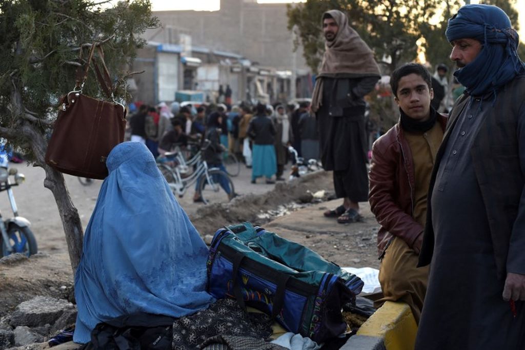 Seorang wanita bercadar mencoba menjual tas bekas di pasar di kawasan Darwaza-e-Kandahar di Herat pada 3 Februari 2022. Busana seperti ini menjadi sangat jamak di bawah Taliban, setelah 20 tahun sebelumnya perempuan Afghanistan mengenakan pakaian lebih terbuka atau berkerundung saja.