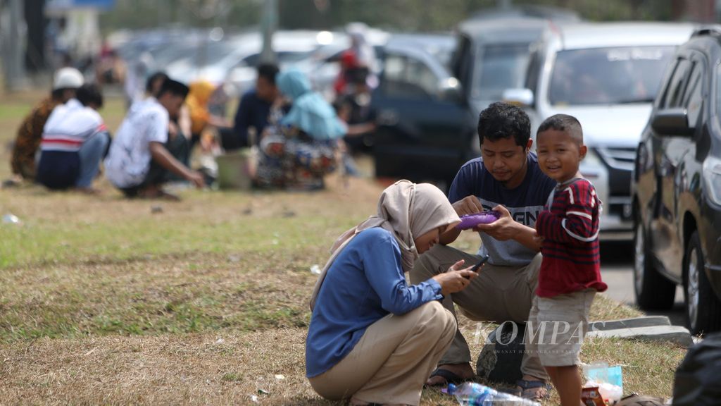 Warga makan di samping mobil mereka yang diparkir di tempat istirahat atau <i>rest area</i> Km 86 Tol Cikopo-Palimanan, Subang, Jawa Barat, pertengahan Agustus 2020.