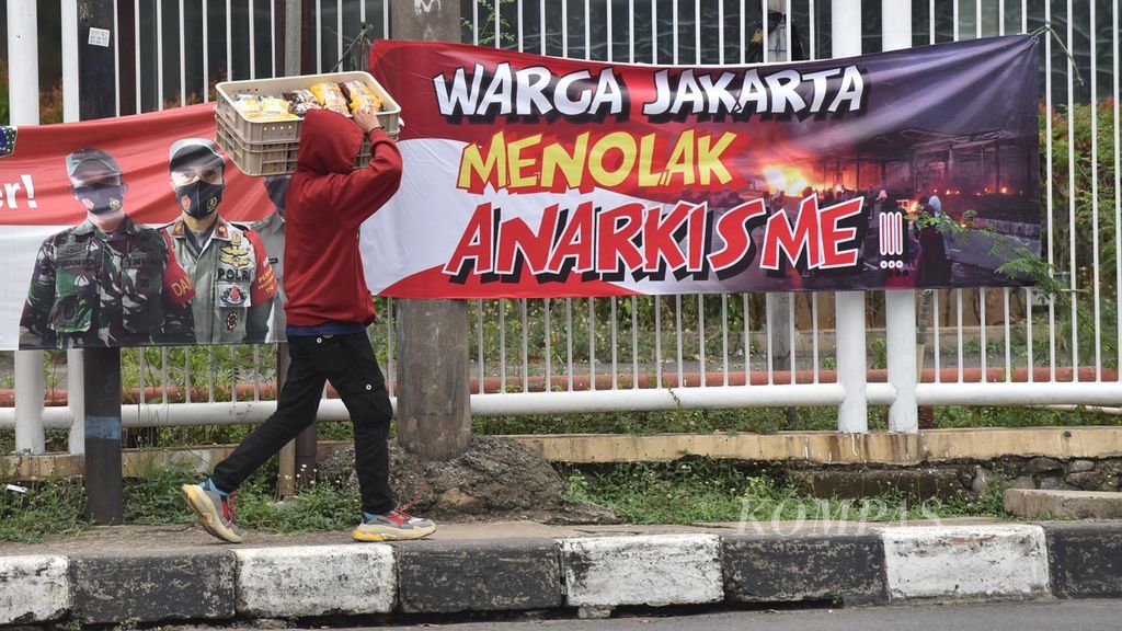 Residents pass near a banner containing a rejection of anarchism at the Pasar Kebayoran Lama intersection, Jakarta,  on Tuesday (13/10/2020).