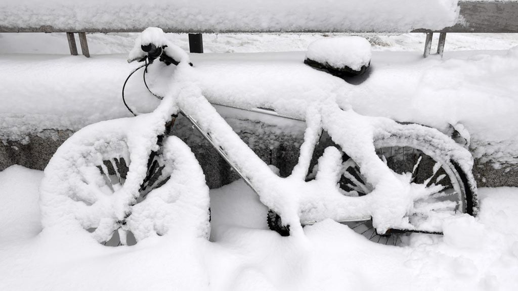 Salju menyelimuti sepeda milik warga yang diparkir di pinggir jalan di Munich, Jerman, Kamis (10/1/2019).