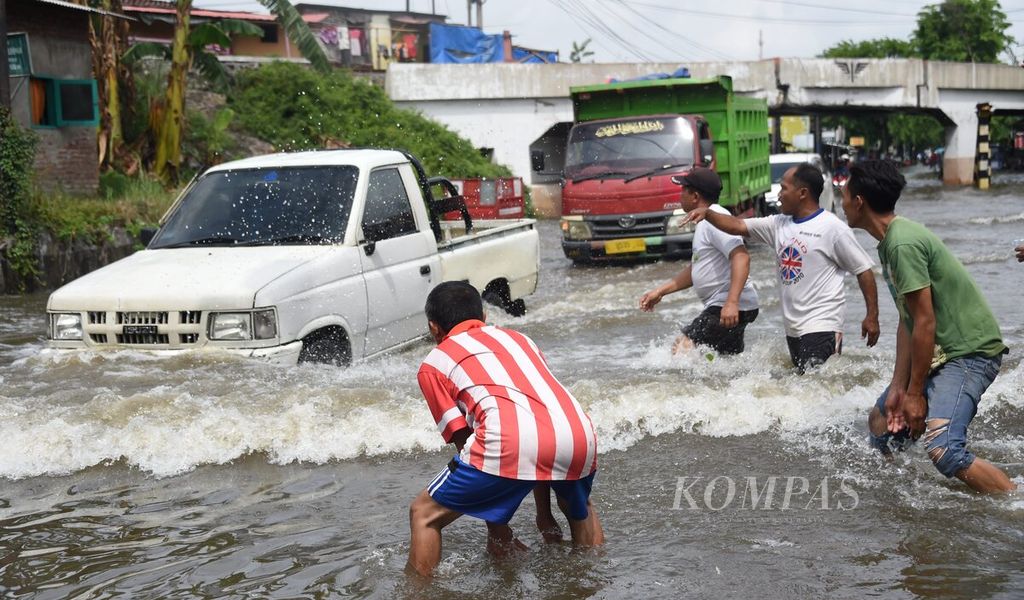 Ilustrasi. Warga meminta pengendara mengurangi kecepatan saat banjir di Jalan Raya Gempol, Kecamatan Gempol, Kabupaten Pasuruan, Jawa Timur, Senin (2/11/2020). 