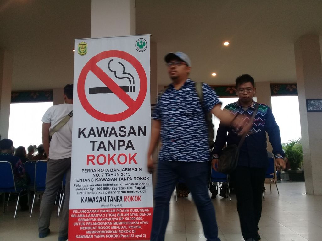 Pengunjung Menara Pandang Wisata, Banjarmasin, Kalimantan Selatan, melintas di samping baliho kawasan tanpa rokok, Jumat (19/1).