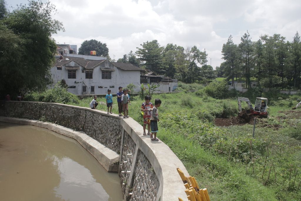 Sejumlah anak mengamati alat berat yang sedang mengeruk lahan di lahan kolam retensi dari pinggir Sungai Cilember di Kelurahan Pasirkaliki, Kecamatan Cimahi Utara, Kota Cimahi, Jawa Barat, Rabu (17/11/2021).
