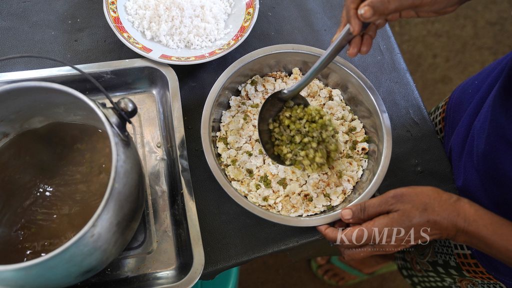 Kuah dan kacang hijau dituangkan diatas jagung titi dalam proses pembuatan menu <i>wata snem</i><i>a</i> di kebun Bayolewung, Pulau Adonara, Kabupaten Flores Timur, Nusa Tenggara Timur, Rabu (9/8/2023). <i>Wata snem<span>’</span>a</i> menggunakan adukan jagung yang dicampur kacang hijau dan parutan kelapa.
