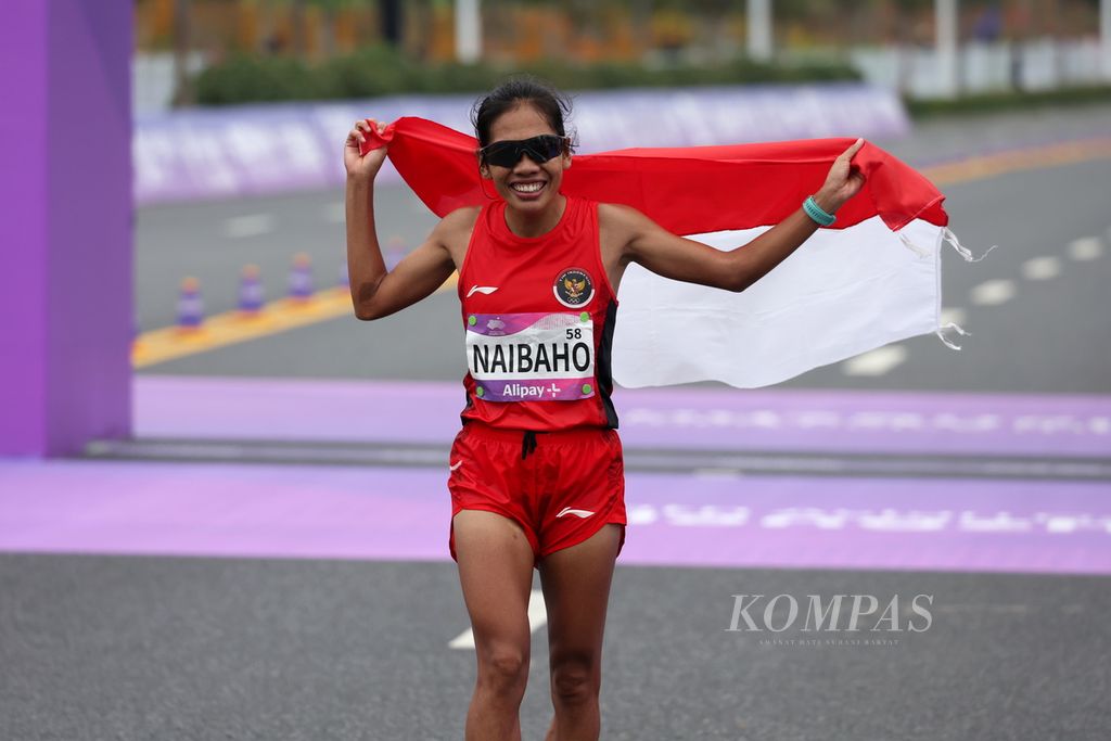 Pelari jarak jauh Indonesia, Odekta Elvina Naibaho, membawa bendera Merah Putih seusai memasuki garis finis dalam maraton putri Asian Games Hangzhou 2022 mengelilingi Qiantang River Green Belt di Provinsi Zhejiang, China, Kamis (5/10/2023). 