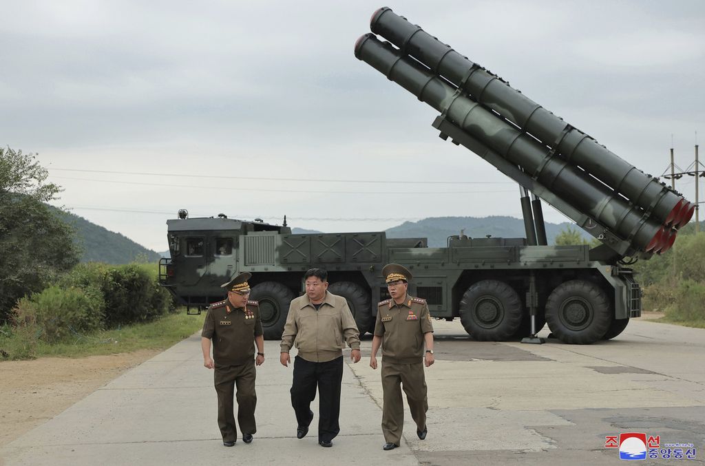 Dalam foto yang ditayangkan Jumat (13/9/2024) oleh Pemerintah Korea Utara, Pemimpin Korea Utara Kim Jong Un (tengah) berjalan dengan pejabat lainnya di dekat wahana peluncur baru roket ganda 600 mm di lokasi yang dirahasiakan di Korea Utara. 