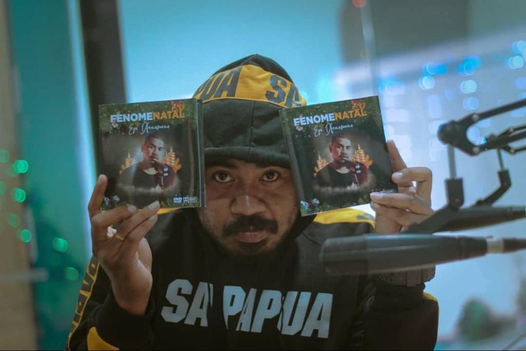 Penyanyi rap asal Papua, Epo D'Fenomeno, menunjukkan salah satu album solo miliknya yang berjudul <i>Fenomenatal</i>. Album ini berisi lagu tentang suasana natal di daerah-daerah Papua.