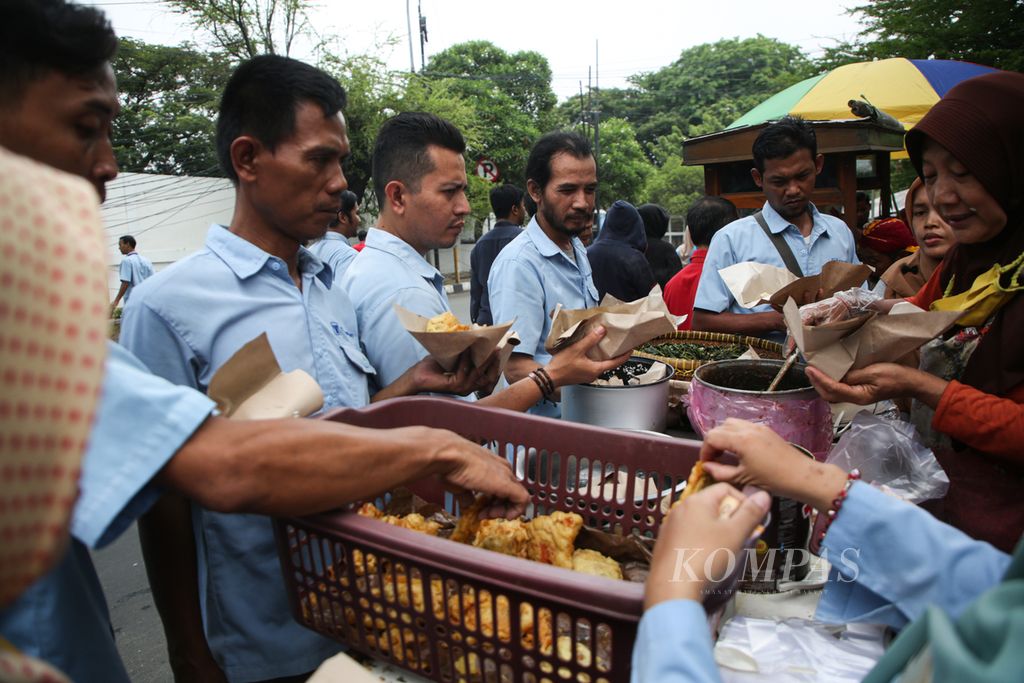 Para buruh membeli makanan dari pedagang di luar area pabrik saat jam makan siang di kawasan Karawaci, Kota Tangerang, Banten, Rabu (22/11/2023).  