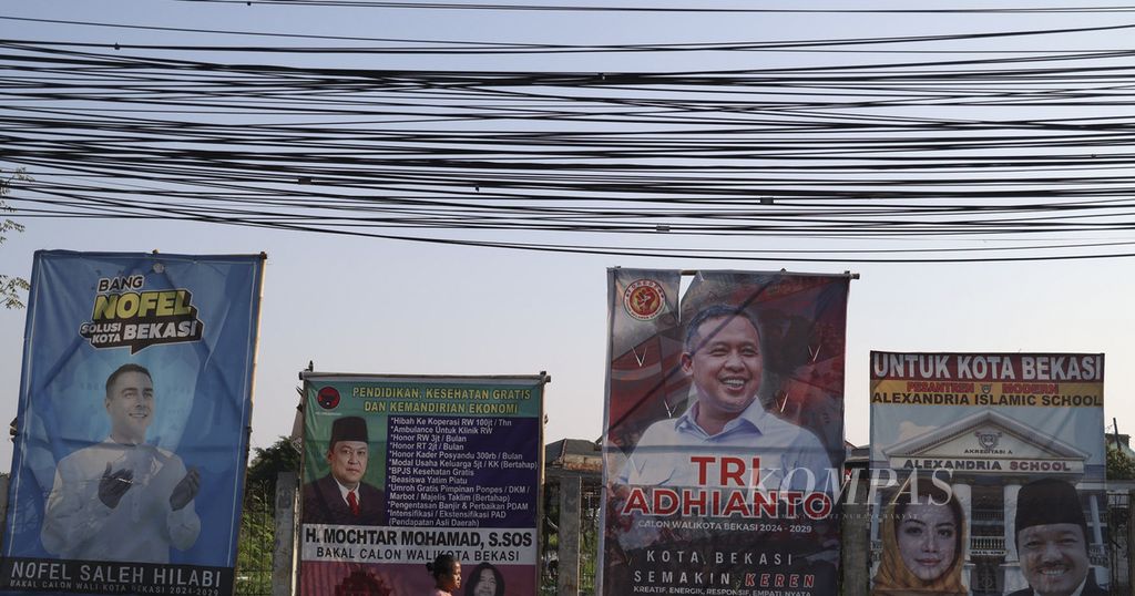 Warga melintas di dekat papan sosialisasi diri bakal calon kepala daerah di kawasan Pondok Gede, Bekasi, Jawa Barat, Jumat (9/8/2024). 