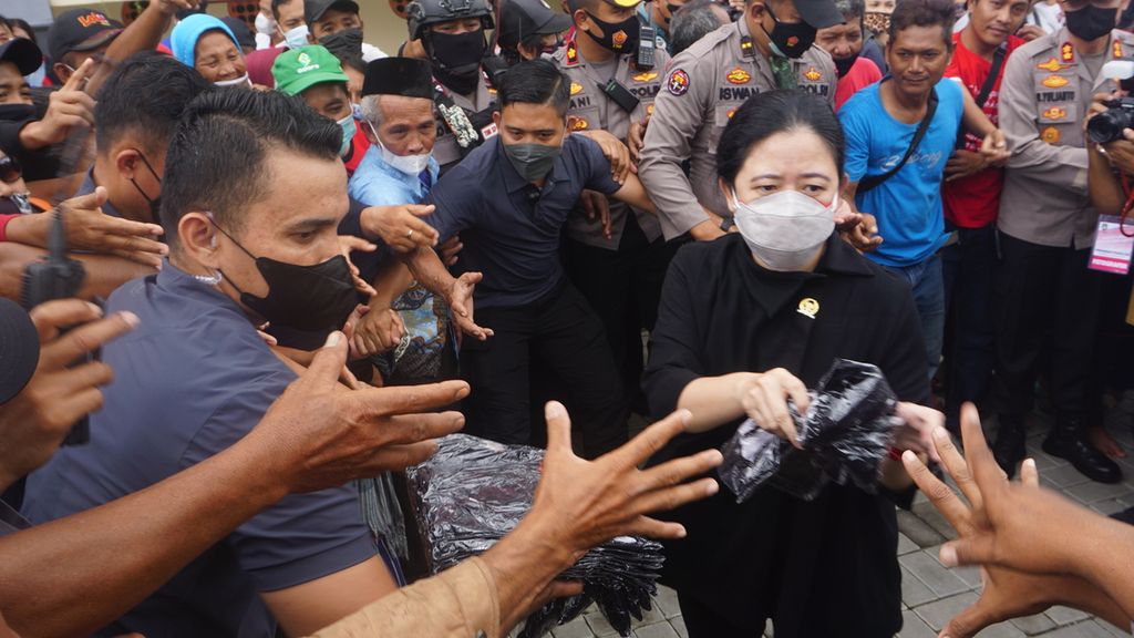 Ketua DPR Puan Maharni (kanan) membagikan kaus kepada para pedagang di Pasar Legi, Kota Surakarta, Jawa Tengah, Kamis (20/1/2022), Aksi itu dilakukan seusai meresmikan salah satu pasar tradisional terbesar di kota tersebut. Pasar dibangun kembali akibat kebakaran pada 2018.