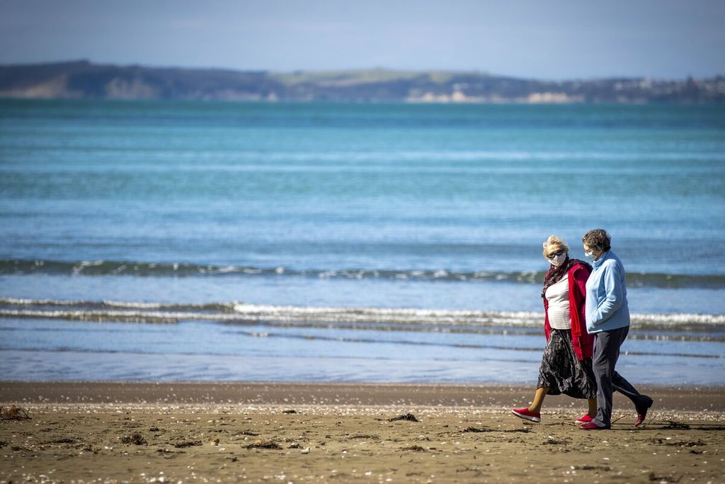 Warga berjalan di sepanjang pantai di Auckland, Selandia Baru, Rabu (25/8/2021). Pemerintah Selandia Baru memperkirakan sekitar 70.000 rumah rawan terdampak kenaikan permukaan air laut sebagai akibat dari perubahan iklim. (Michael Craig/NZ Herald via AP)