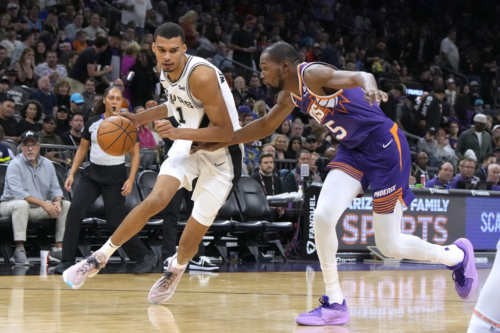 <i>Center</i> San Antonio Spurs, Victor Wembanyama, dibayangi <i>forward</i> Phoenis Suns, Kevin Durant, dalam pertandingan NBA antara Spurs dan Phoenix Suns di Footprint Center, Jumat (3/11/2023) WIB. Spurs mengalahkan Suns, 132-121.