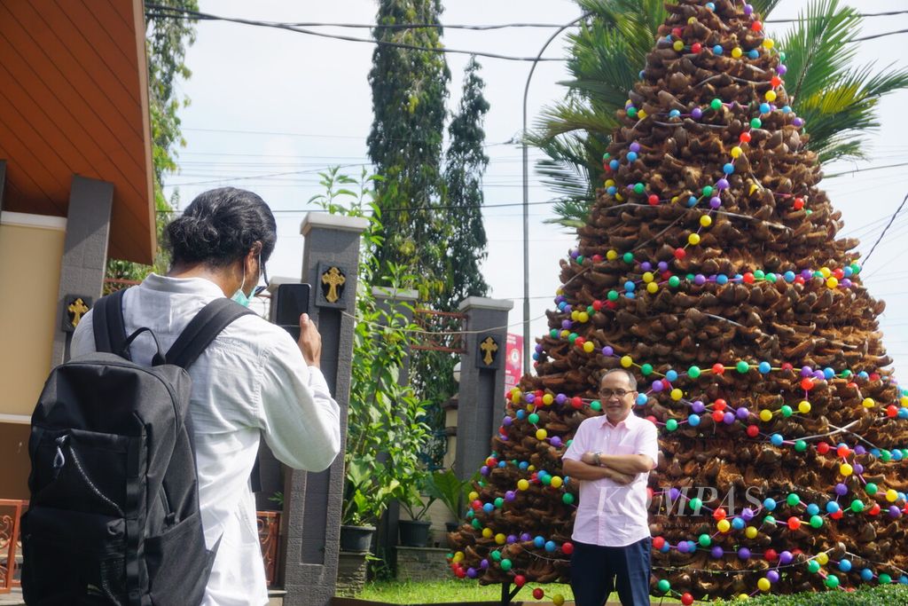 Anggota jemaat berfoto di depan pohon natal berbahan sabut kelapa yang dibuat di Gereja Katedral Kristus Raja Purwokerto, Banyumas, Jawa Tengah, Kamis (22/12/2022). 