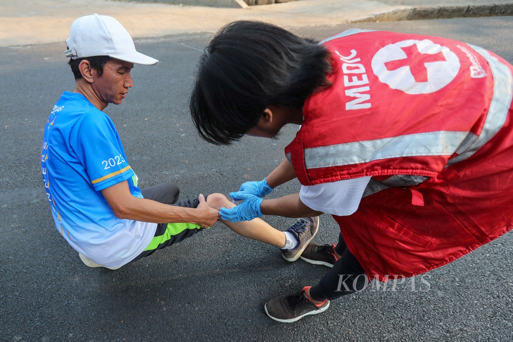 Petugas medis memberikan pertolongan pertama kepada pelari yang cedera saat mengikuti ISOPLUS RSUI Run di kawasan Universitas Indonesia, Kota Depok, Jawa Barat, Minggu (8/10/2023).