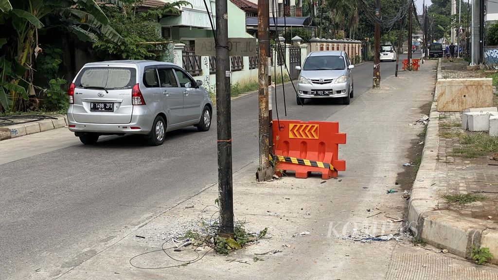 Pengendara melintasi deretan tiang kabel yang memakan badan di Jalan Bukit Cinere Raya, Gandul, Depok, Jawa Barat, Minggu (22/8/2021). 