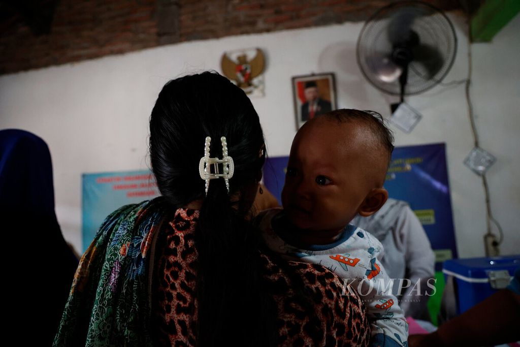 Salah satu ibu mengggendong anak balitanya agar mendapatkan imunisasi polio di Posyandu Mekarsari, Kampung Tambakrejo, Kota Semarang, Jawa Tengah, Senin (15/1/2024). 