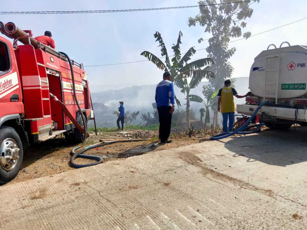 Petugas pemadam kebakaran memindahkan air dari mobil tangki di sekitar tempat pemrosesan akhir sampah di Desa Penujah, Kecamatan Kedungbanteng, Kabupaten Tegal, Jawa Tengah, Jumat (30/6/2023).