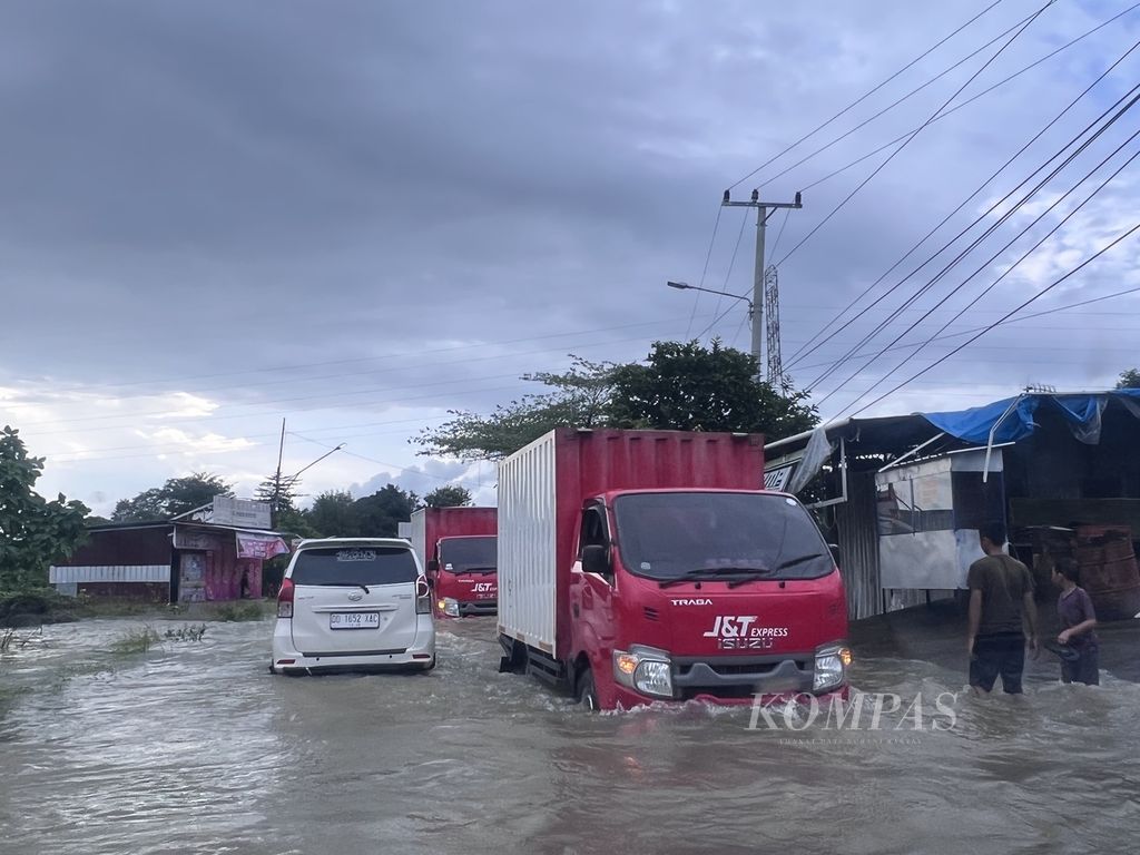 Kendaraan melintasi banjir di jalan Poros Patte’ne di perbatasan Makassar-Maros, Sulsel, Selasa (14/2/2023).