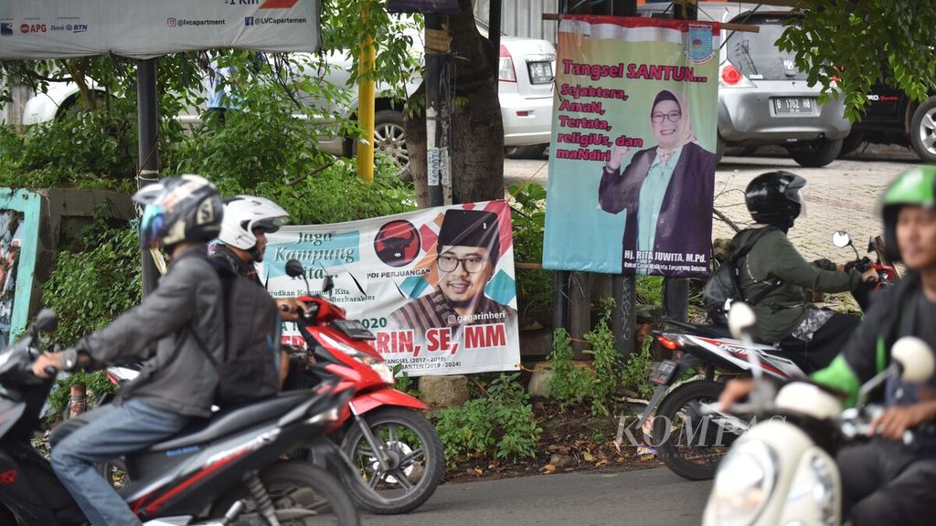 Motorcycle riders pass by a poster of a prospective candidate for mayor in the 2020 South Tangerang City Mayoral Election on Aria Putra Street, Ciputat, South Tangerang, Banten, on Saturday (18/1/2020).