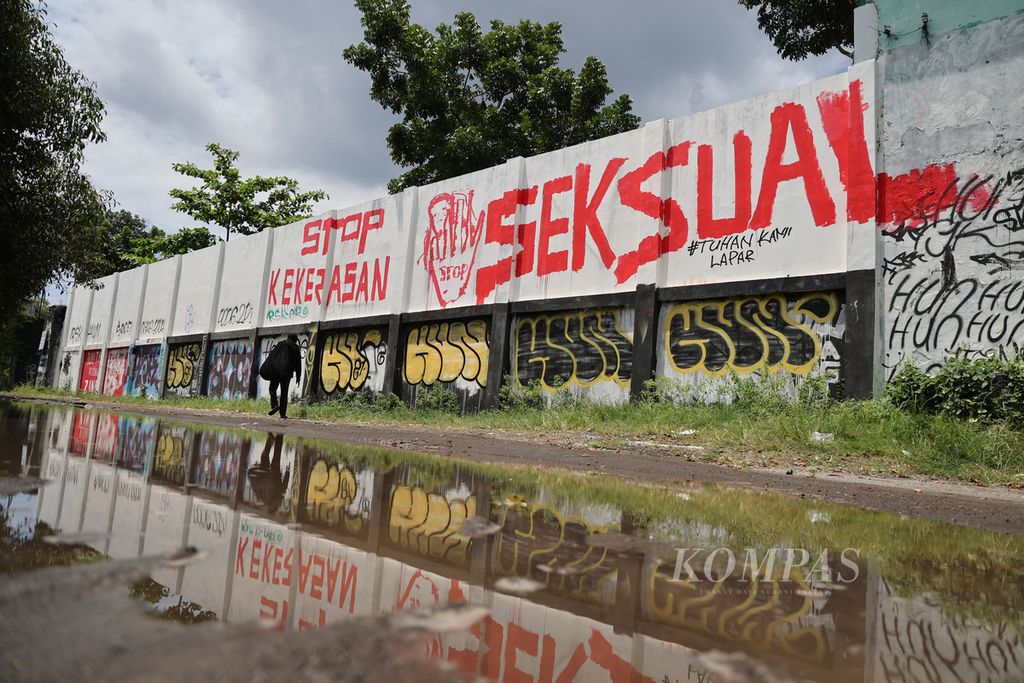 Warga melintas di depan mural berisi seruan untuk menghentikan segala bentuk kekerasan seksual yang dibuat di tembok Stadion Kridosono, Yogyakarta, Senin (10/1/2021).