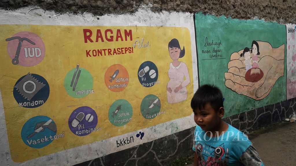Seorang anak melintasi mural bergambar ragam kontrasepsi di Kampung KB, Bintara Jaya, Kota Bekasi, Jawa Barat, Februari 2023.