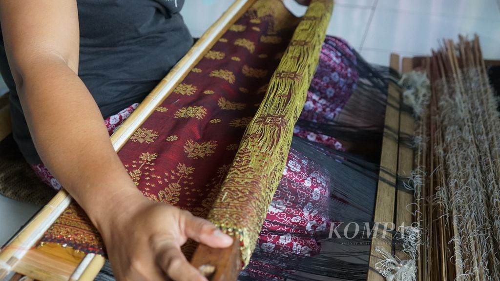 Seorang petenun di Desa Muara Penimbung, Kecamatan Indralaya, Kabupaten Ogan Ilir, menenun songket di rumahnya, Kamis (10/3/2022). Kawasan ini dijuluki kampung songket karena penduduknya memiliki kemampuan membuat songket. Hasil songket mereka dipasarkan ke Palembang dan beberapa kota lain di Indonesia,