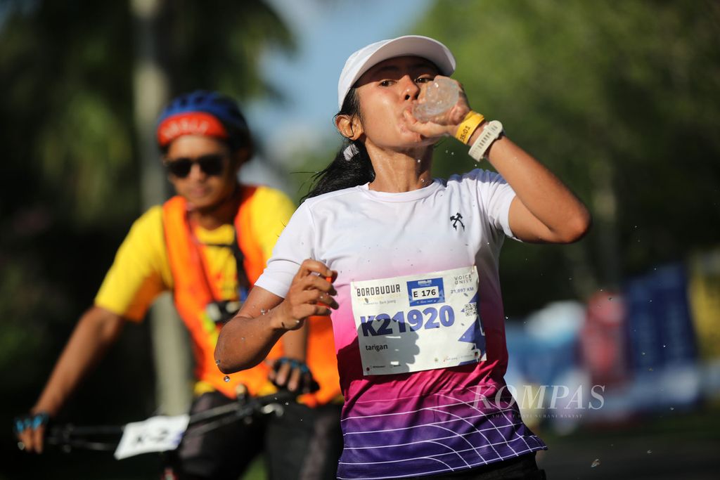 Isania Tarigan minum saat berlomba dalam ajang Borobudur Marathon 2023 Powered by Bank Jateng kategori separuh maraton di Magelang, Jawa Tengah, Minggu (19/11/2023). 