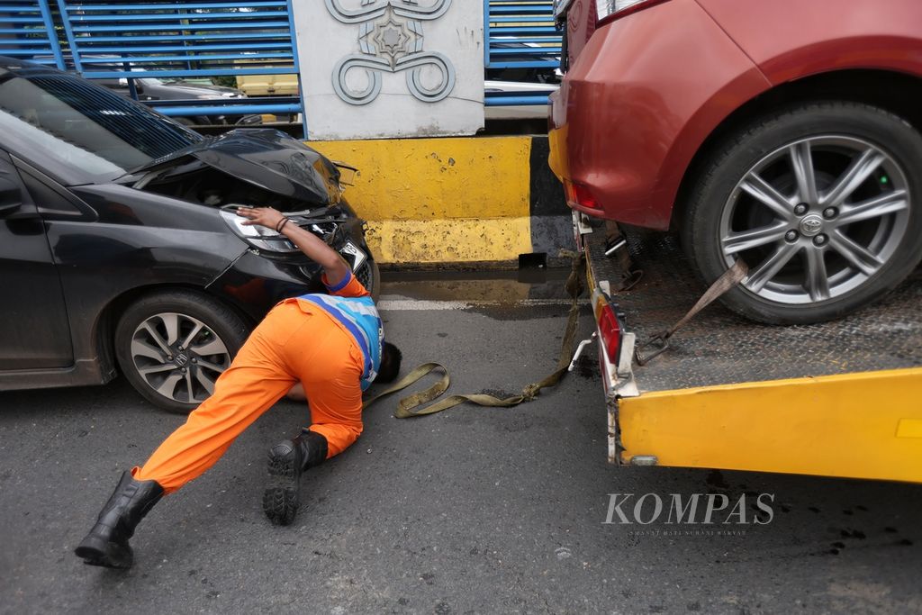 Petugas memasang tali derek ke salah satu mobil yang mengalami kecelakaan di Gerbang Tol Halim Utama, Jakarta, Rabu (27/3/2024). Terjadi kecelakaan beruntun tujuh kendaraan di Gerbang Tol Halim Utama. Kecelakaan terjadi akibat supir truk yang diduga mengendarai secara ugal-ugalan. 