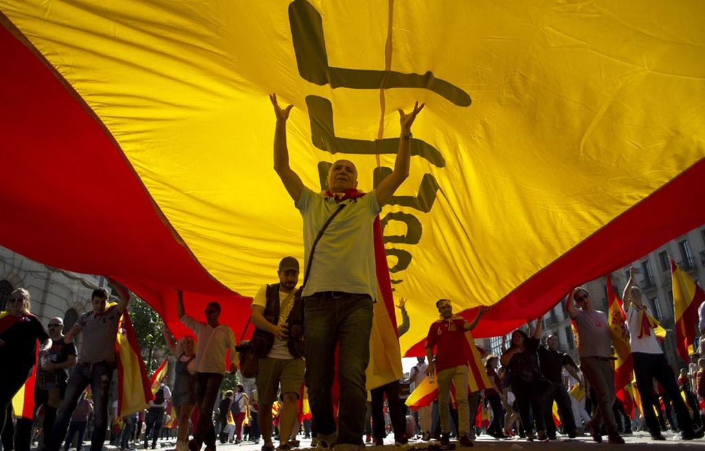 Para pengunjuk rasa membawa bendera raksasa Spanyol dalam demonstrasi yang diikuti Masyarakat Sipil Catalan untuk mendukung persatuan Spanyol, Minggu (8/10).
