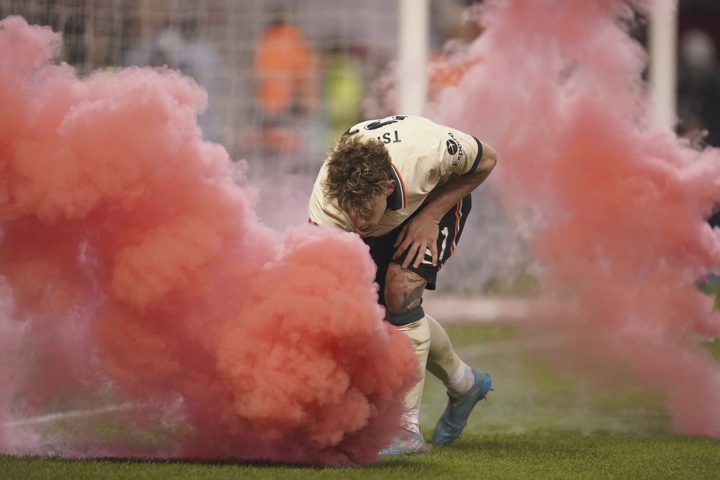 Bek Liverpool, Kostas Tsimikas, membuang bom asap yang dilempar penonton ke dalam lapangan pada laga perempat final Piala FA antara Liverpool dan Nottingham Forest di Stadion City Ground, Nottingham, Inggris, 20 Maret 2022. 