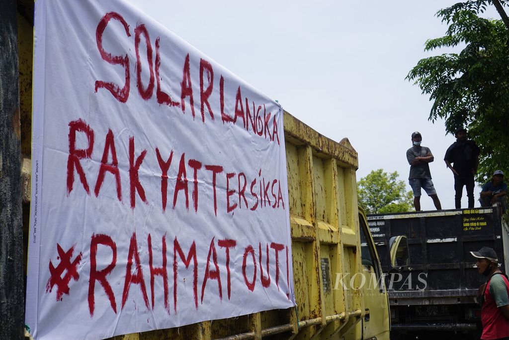 Sopir truk membentangkan spanduk tuntutan di bak truk saat berunjuk rasa di depan Kantor Wali Kota Balikpapan, Kalimantan Timur, Rabu (30/3/2022). Sedikitnya 250 truk dibawa dalam demonstrasi menuntut distribusi merata solar bersubsidi ini.