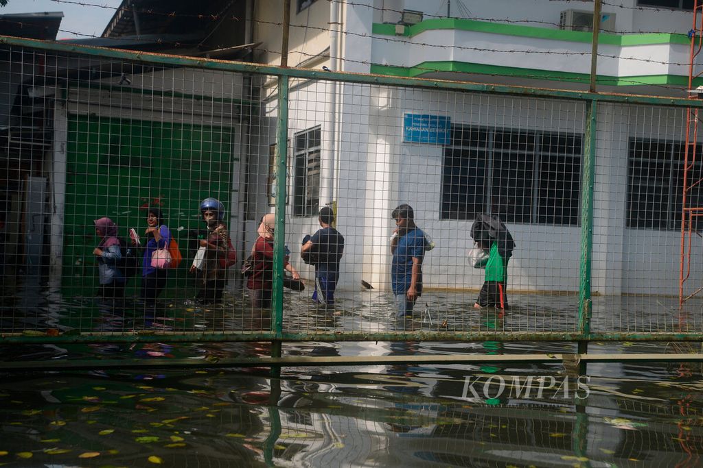 Buruh pabrik dikerahkan untuk membersihkan tempat mereka bekerja di tengah genangan banjir pasang air laut di kawasan berikat Pelabuhan Tanjung Emas, Kota Semarang, Jawa Tengah, Jumat (27/5/2022).
